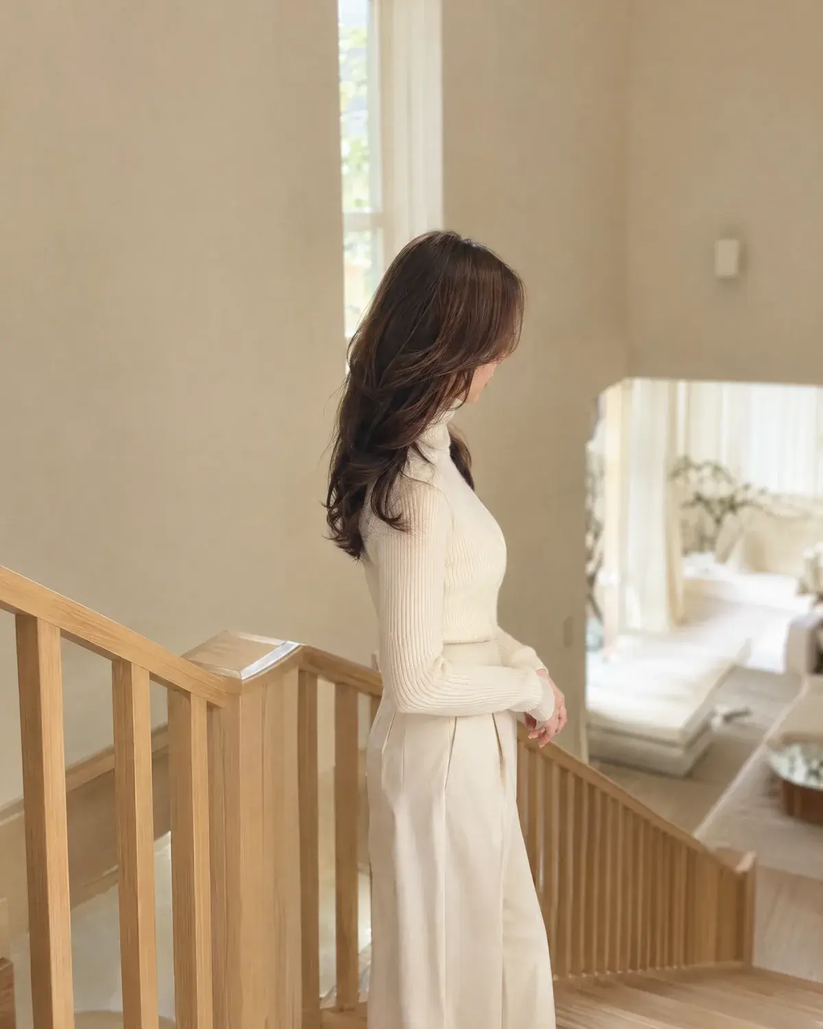 가슴 길이 웨이브 머리의 여성이 나무 계단 옆에 선 옆모습